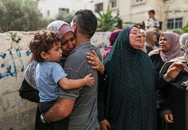 A Palestinian family embraces with tears running down their faces.