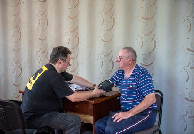 An IRC staff member provides medical attention to an elderly man. 