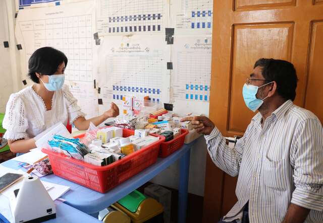 An IRC clinic nurse sits across from a patient who she gives medical advice to.