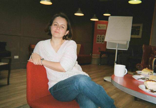 Halyna sits on a chair, facing the camera.