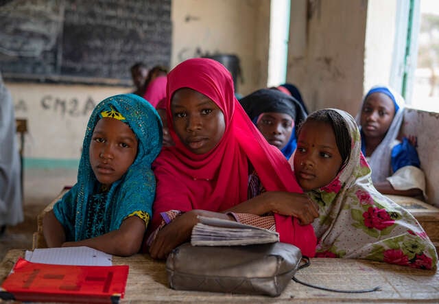 Maryama och hennes klasskompisar sitter vid ett bord i ett klassrum i Niger.