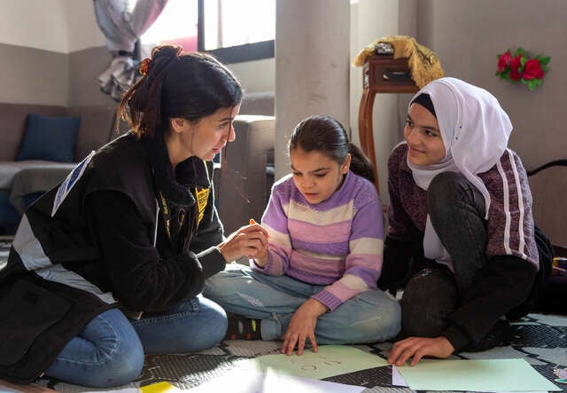RESCUE:s medarbetare sitter på golvet och pratar med två tjejer under en aktivitet i Libanon, där flickor och kvinnor får stöd.