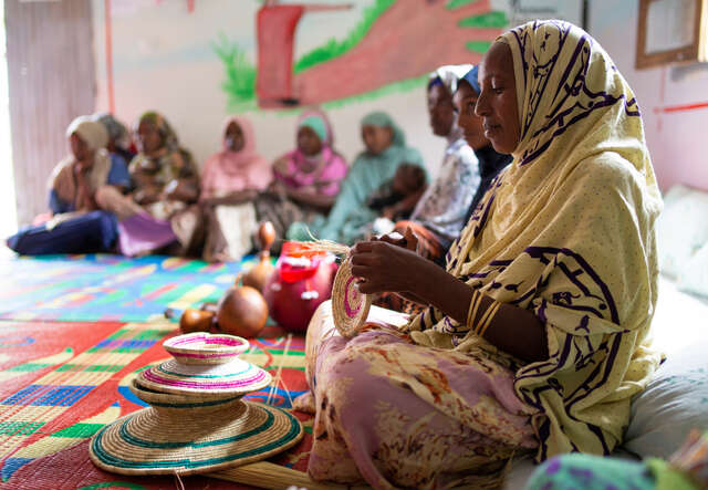 Flera kvinnor sitter på golvet och lär sig att göra traditionellt hantverk på en trygg plats för kvinnor och flickor i Etiopien. 