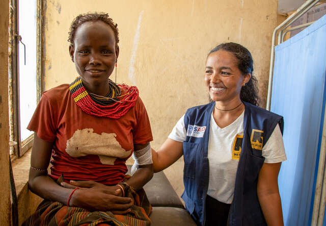 An IRC client sits beside an IRC health and nutrition officer in Ethiopia, they share a smile.
