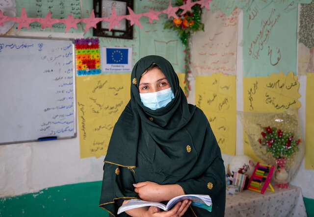 Hajera reads a book aloud from a book to her students.