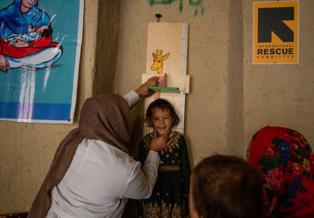 IRC nutrition counselor, Faiza Irfani, checks the height of Rozama’s daughter, Fahmia, on the stadiometer.
