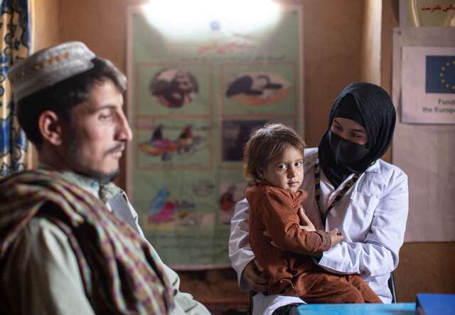 IRC counsellor, Ruqia Moqtased, holds 2 year-old Samia to do a health check-up