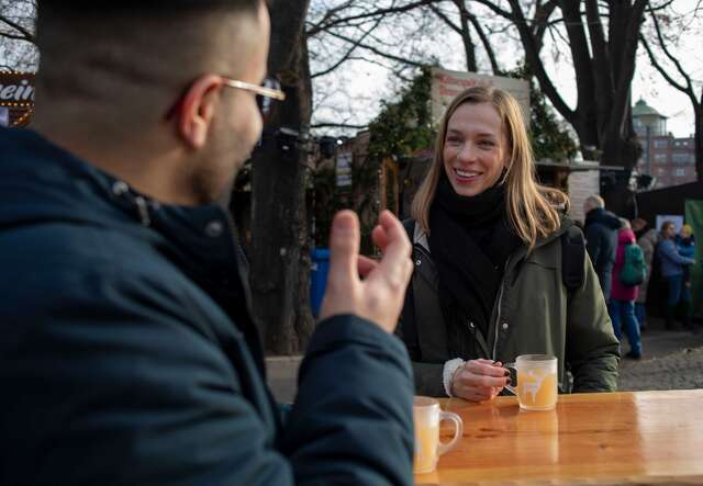 Eine Frau und ein Mann unterhalten sich auf dem Weihnachtsmarkt.