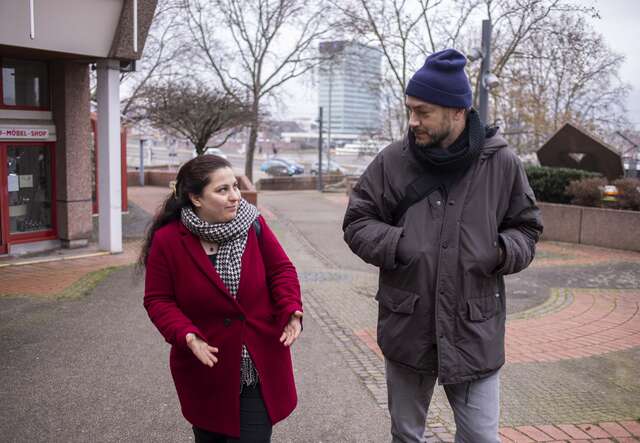 Eine Frau und Mann tragen Winterkleidung und sprechen miteinander.