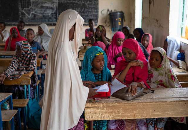 A teacher speaks with students at a school in Niger.