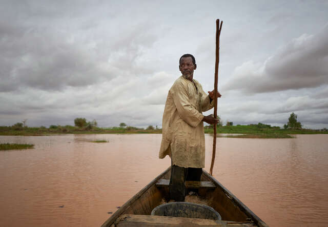 A man in Niger navigates a flooded areas in a boat.