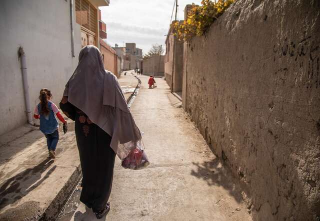 Noor* takes her daughter to the local market to purchase food for her and her children using the emergency cash assistance provided to her by the International Rescue Committee.