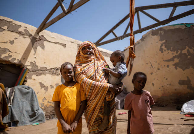 Altuma stands in her temporary house with her three children.