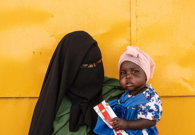 17-month old Safia holds a packet of fortified peanut paste rich in nutrients and calories. Farchana camp, Chad. 