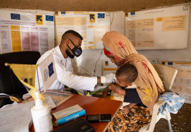 IRC consultant, Dr. Mogahed, works with a client and her child at an IRC medical clinic in Sudan.