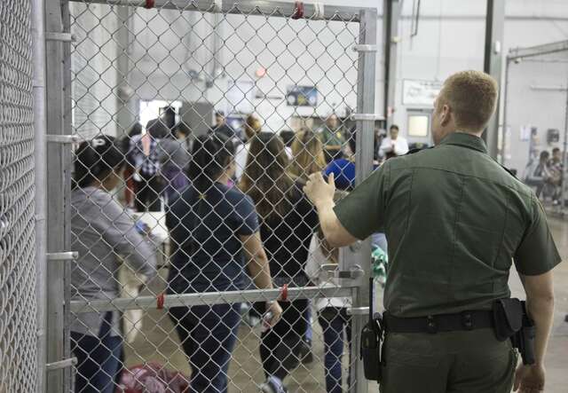 A US Border patrol agent prepares to close a metal fenced-door at a facility in Texas.