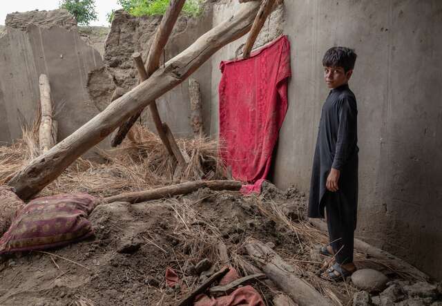 Abas, a twelve year old Afghan boy, stands in the remains of his home which was destroyed by a severe flood.