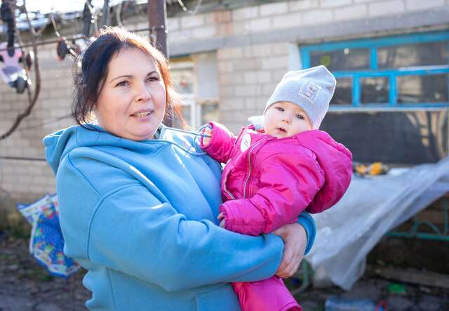En ukrainsk mamma håller sitt barn i famnen, utomhus med vinterkläder. De har fått hjälp från RESCUE för att klara vintern.