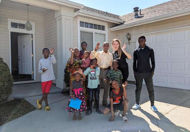 The Ruhararas celebrate in front of their new home with their housing coordinator.