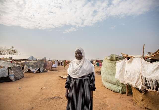 A woman stands outside her makeshift home in a camp for internally displaced people.