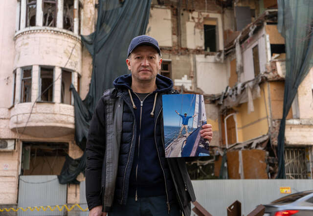 Andrii hält ein Foto von sich auf einer Yacht. Es entstand während seiner Reisen vor dem Krieg.
