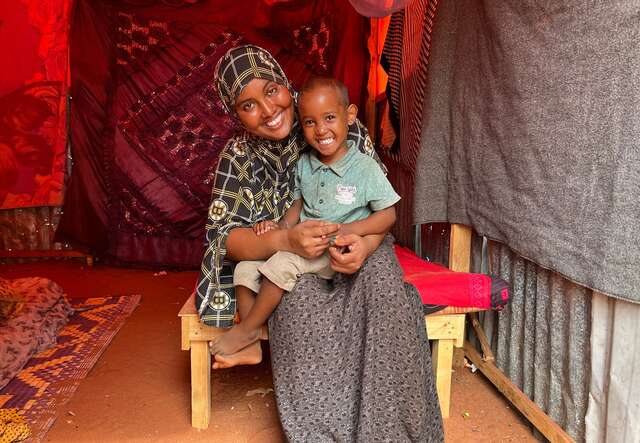 A woman sits with her son on her lap