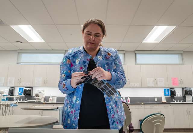 A dental assistant reviews x-rays in an office, located in San Diego, CA.