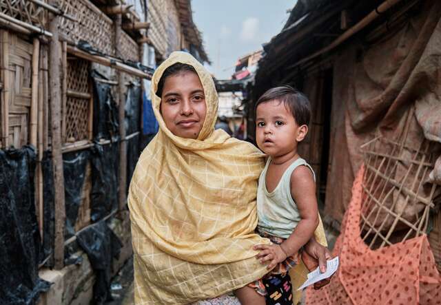 An IRC client and Rohingya refugee holds her son in her arms near their home in the Cox'z Bazar refugee camp in Bangladesh.