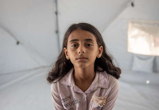 Ruba, a ten year old Palestinian girl, sits in a tent.