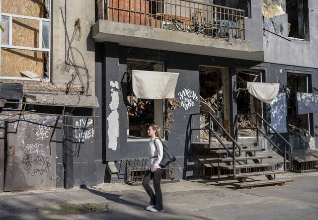 A woman walks by war torn streets after work