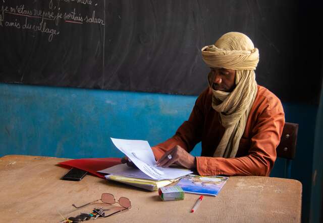 Gao, Mali. A teacher at his desk observing a document.