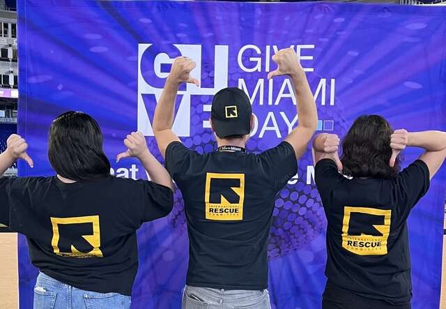 IRC Staff proudly display their IRC shirts in front of the Give Miami banner