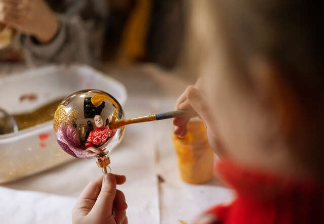 A child decorates a Christmas bauble