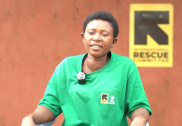 A woman in an IRC branded green polo is seated and smiling at the camera 