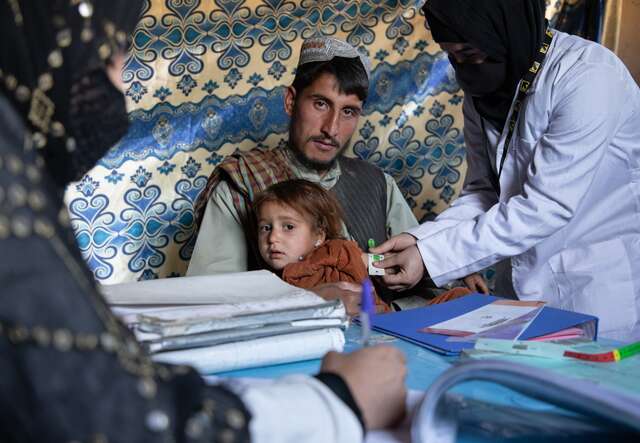 An IRC health worker screens a young girl for malnutrition in Afghanistan.