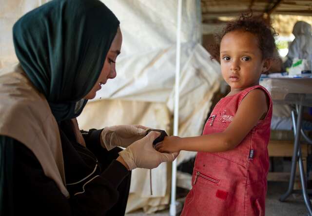 An IRC health worker performs a health check up a young girl in Lebanon.
