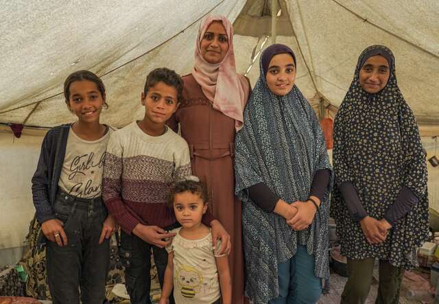 A family of Palestinians pose for a photo in their temporary shelter in Khan Younis, Gaza.