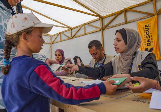An IRC staff member distributes winter clothing to a child in Gaza.