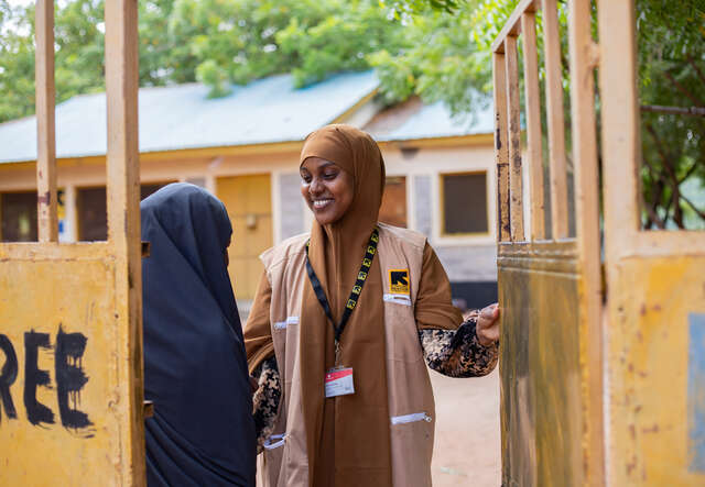 Två kvinnor står och pratar vid en grind.