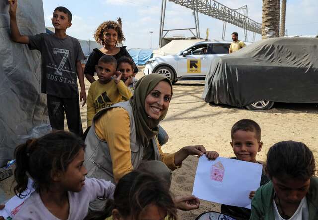 Child Protection Manager, Faten, with children showing their artwork in Khan Younis, Gaza.
