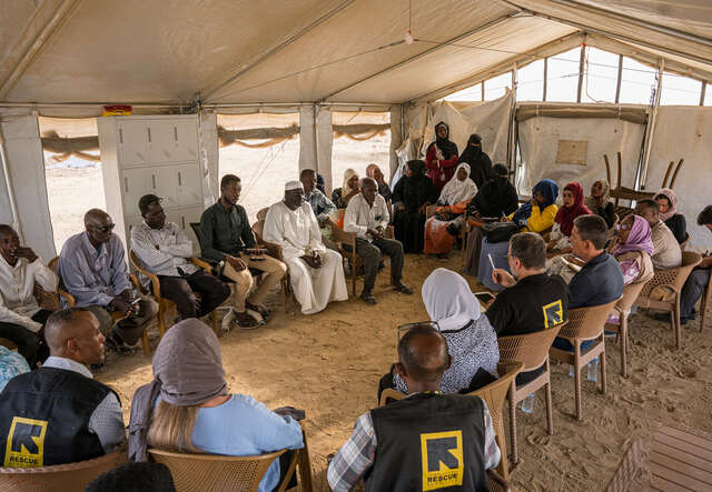 Flera av RESCUE:s medarbetare sitter i en cirkel i ett tält och samtalar. 