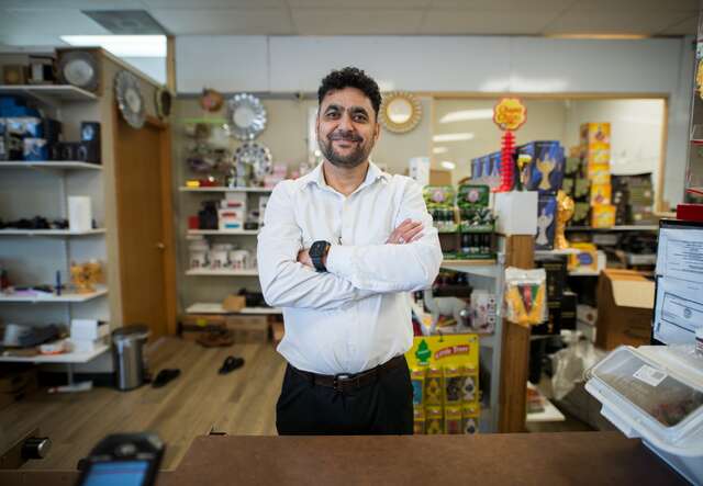 Ahmed stands behind the counter at his small business.