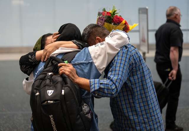 A family of three share a big embrace after reunifying at a U.S. airport.