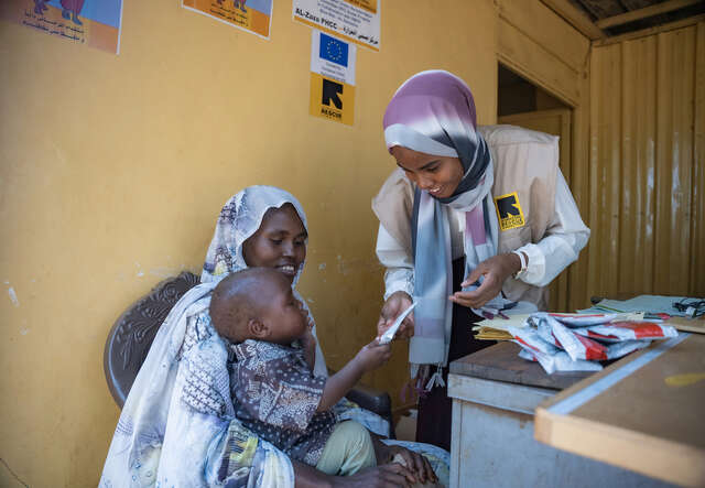 한 어린이와 엄마가 영양실조 치료센터에서 치료식을 받고 있습니다.