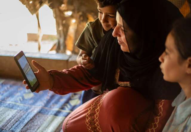 Halima zeigt ihren Kindern ein Video von ihrem Dorf in Syrien.