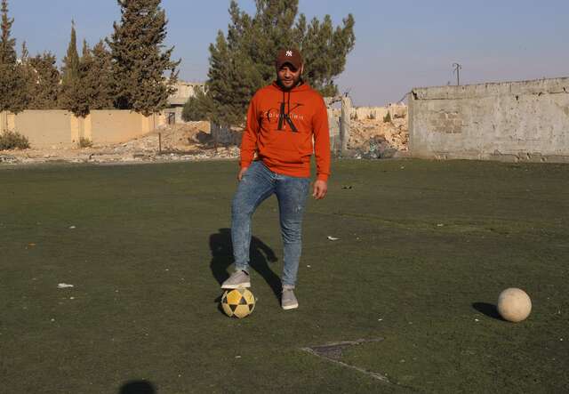 Al-Qusayr, Homs province, Syria. Mohammad, 38, balances a football on the field he helped restore with other returnees for local children.