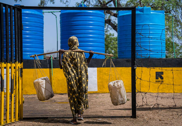 Nusaiba bär på vattendunkar, på väg till en av RESCUE:s vattenstationer. 