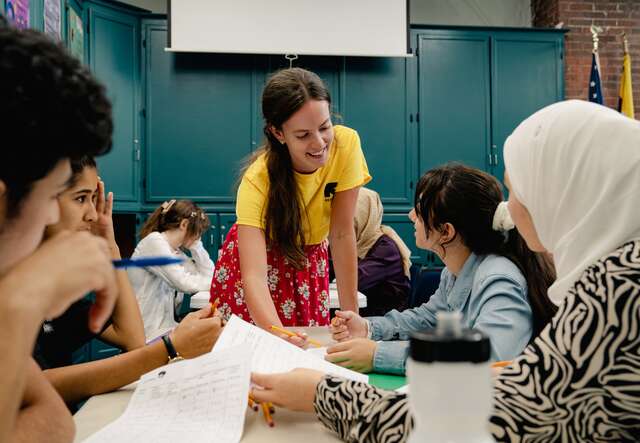 An IRC volunteer assists students at an IRC summer school.