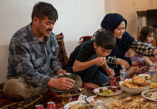 Familjen Hussaini sitter på golvet och delar iftar tillsamans. 