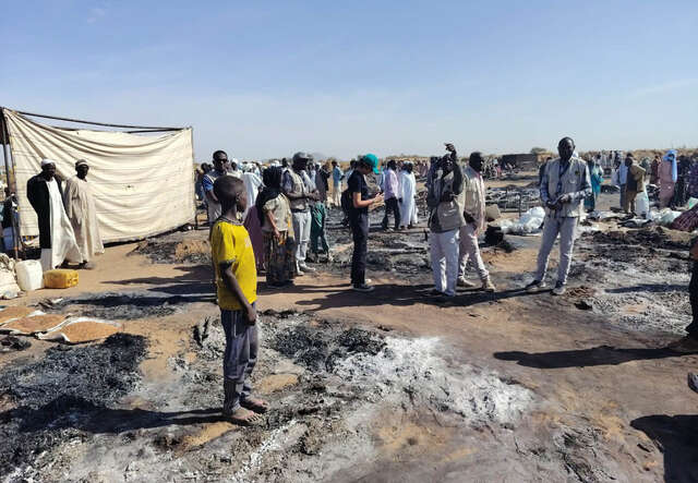 En pojke står på aska i ett nedbränt flyktingläger i Tawila, Sudan. 